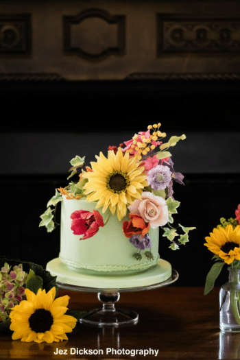 Pale green celebration cakes with handcrafted sugar flowers on top.