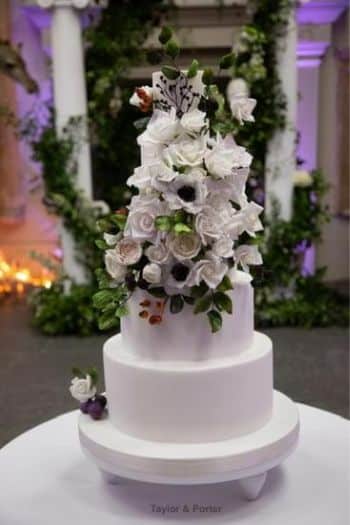 4 tier white wedding cake with handcrafted sugar flowers and leaves.